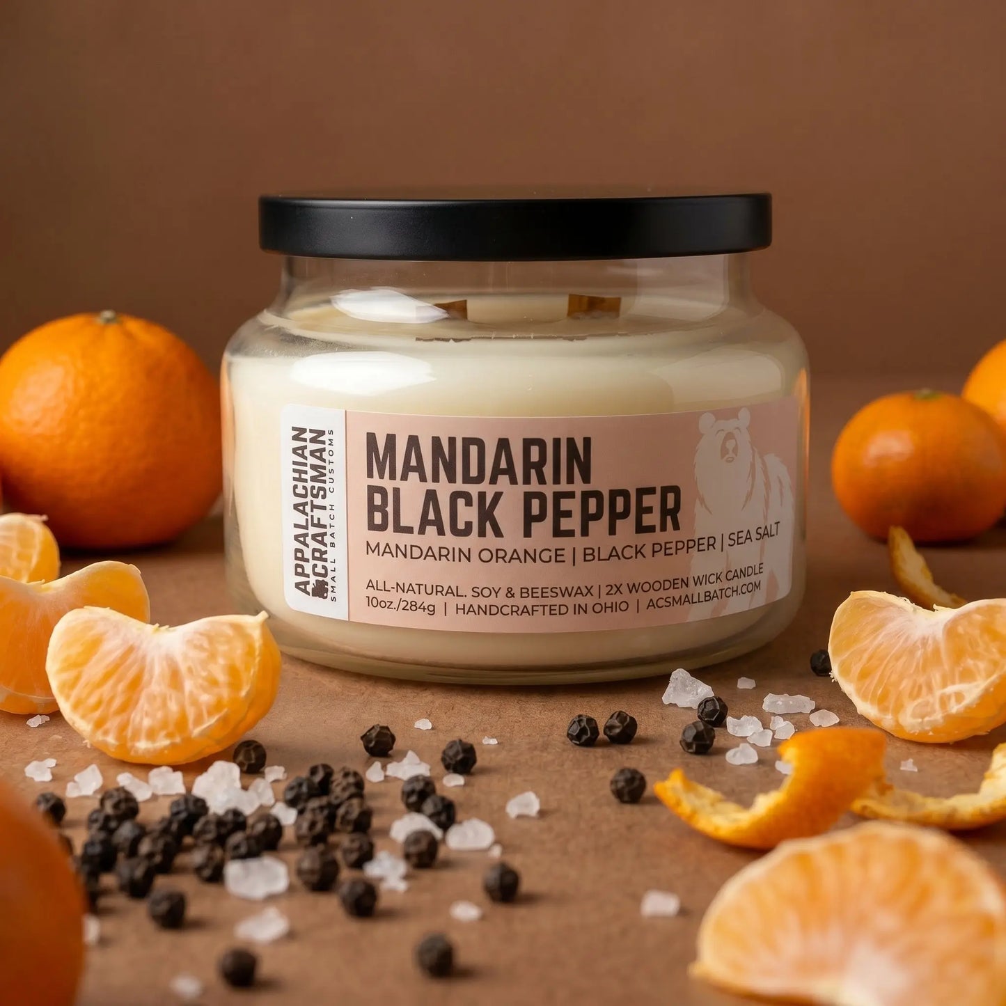 Candle jar labeled 'Mandarin Black Pepper' with mandarin oranges and black peppercorns on a brown background